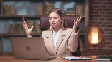 Young businesswoman feeling pissed of because of getting negative result and failing project. Frustrated female worker looking desperately at laptop screen and spreading hands.