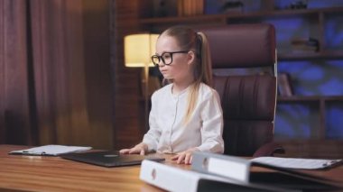 Angle view of little business lady feeling pissed of because off getting negative result and failing project. Frustrated child closing laptop and expressing negative emotions at modern office.