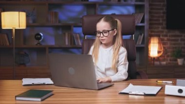 İki at kuyruklu sevimli genç kız çevrimiçi piyango kazanıyor ve modern ofiste bilgisayarda bilgilendirme alıyor. Dinamik çocuk haykırıyor, ellerini uzatıyor ve zafer işareti yapıyor..