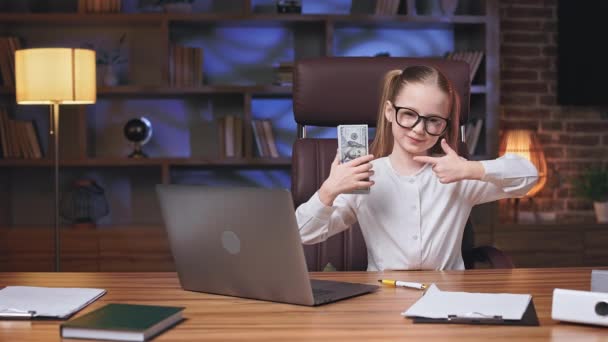 Mała Biznesmenka Siedząca Przed Laptopem Drewnianym Biurku Trzymająca Stos Dolarów — Wideo stockowe