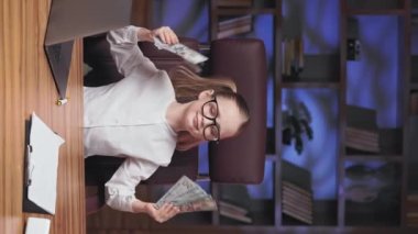 Canlı çocuk, uzaktan kumandalı bir aletle havalı müziğin keyfini çıkarıyor ve elleri para dolu ritmik hareketler yapıyor. Dinamik küçük liseli kız ebeveyn ofisinde eğleniyor. Dikey video.