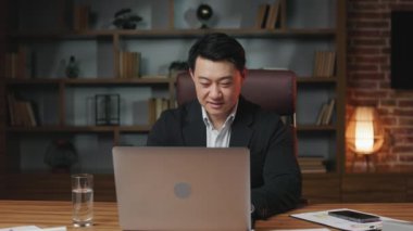 Koyu saçlı pozitif Asyalı beyefendi finansal raporuna birkaç cümle yazıp bilgisayarı kapatıyor. İş kıyafetleri içinde neşeli bir çalışan işi bitirip ofisten ayrılıyor..