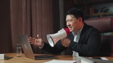 Side view of executive feeling pissed off and yelling in loudspeaker during video conference on portable device. Asian director taking disciplinary action with lazy employees for insufficient work.