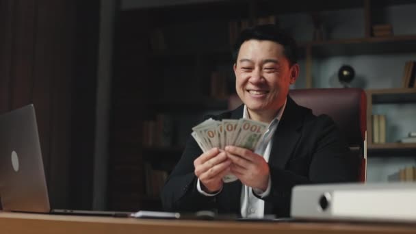 成功的亚洲投资者在舒适的工作环境中与远程小玩艺儿坐在一起 计算钞票 繁荣的人对工作成就和成果感到满意 — 图库视频影像