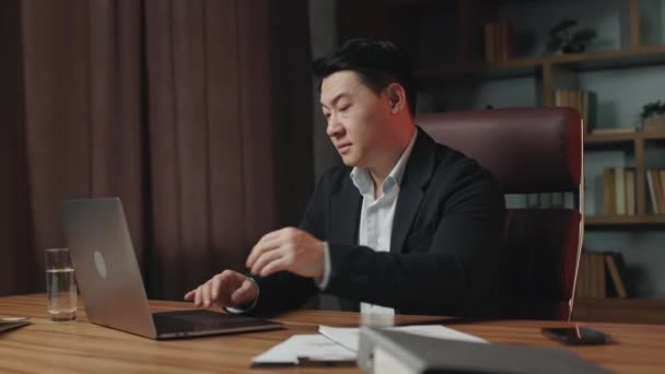 Irritado Asiático Trabalhador Vestido Elegante Preto Terno Sentado Desktop Madeira — Vídeo de Stock