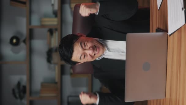 穿着漂亮的员工兴奋地举起拳头 然后在工作时在笔记本电脑屏幕前欢呼 欣喜若狂的亚洲经理获得了新投标的确认 垂直录像 — 图库视频影像