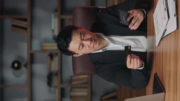 在智能手机应用中 穿着正装的严肃的亚洲企业家在输入信用卡号码 有信心的企业主检查公司在办公室的银行账户的垂直视频 — 图库视频影像