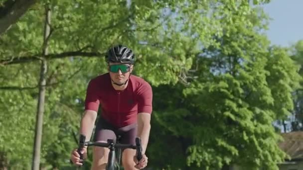 头戴头盔 戴着太阳镜 骑着轻碳公路自行车的高加索人在野外野外的画像 在进行中等强度活动的同时 放松健美的运动员呼吸新鲜空气 — 图库视频影像