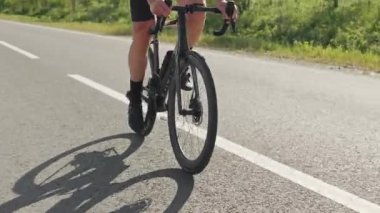 Aktif giyimli, çekici bir adam sıcak yaz güneşi altında kaldırımlı garaj yolu boyunca ata biniyor. Yükselmeden önce pedallara baskı yapmak için vücut ağırlığını kullanan etkili bir bisikletçi..