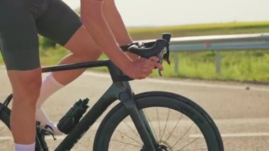 Erkek bisikletçinin dışarıda çalışırken kolları gidonların üzerinde yarış bisikletini süratle sürüşünü yakından izleyin. Dayanıklılık eğitimli sporcu gündüz eğitiminde dengesini koruyor.