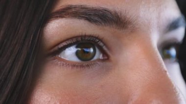 Kahverengi gözlü, saf tenli ve açık renk makyajlı bir kadın yüzü. Koyu renk saçlı dalgın güzel bir kadın. Düz bakıyor ve bir şeyler düşünüyor..