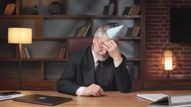 Ofiste sıkı çalıştıktan sonra kafasında doğum günü şapkası olan yorgun bir çalışan dinleniyor. Yorgun profesyonel yönetici sessiz toplantı odasının rahatlığı içinde şirket kutlamalarına ara veriyor..