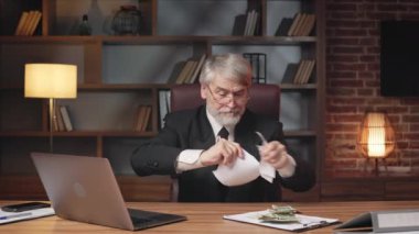 İdari makama atmadan önce kağıt parçalarını yırtan sinirli yaşlı kişinin portresi. Resmi olarak memnun olmayan girişimci çalışırken yazılı sözleşmeyi mahvediyor..