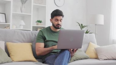 Hintli genç adam evde modern bir dizüstü bilgisayar üzerinde çalışırken inanmayarak başını sallıyor. Erkek serbest yazar, rahat koltukta otururken hayal kırıklığıyla ekranda..
