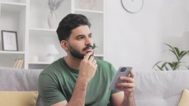 Düşünceli bir milenyum adamı koltukta oturup akıllı telefon tutarken ciddi ciddi uzaktan bakıyor. Yeşil tişörtlü Hindu adam gezici ekrandaki görüntüyü tercüme ediyor ve gülümsüyor..