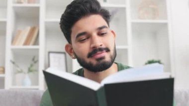 Sakallı Hindu erkek romanının kapanış portresi ve hafta sonları evde dinlenme. İlgi çekici esmer erkek. Kitap rafının arkasında oturuyor. Güzel süslemeleri var..