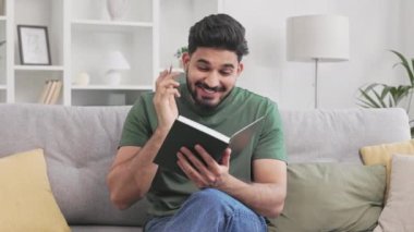Keyifli Hintli adam, hoş bir dairede ilham sırasında not defterine harika bir fikir yazıyor. Sıradan giyinmiş sakallı bir adam kanepede oturuyor ve yüzünde samimi bir memnuniyet var..