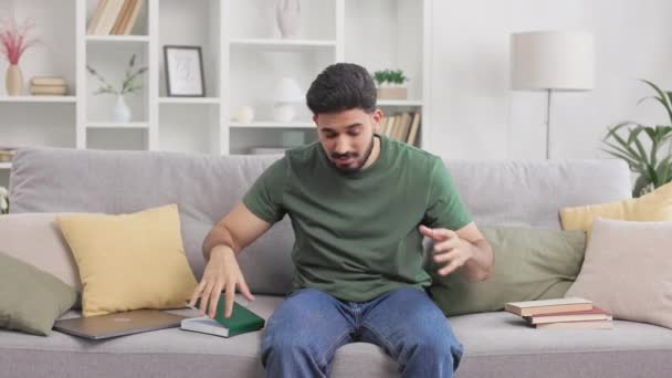 Индийский Студент Мужчина Сидя Диване Окруженный Книгами Испытывает Стресс Домашней — стоковое видео