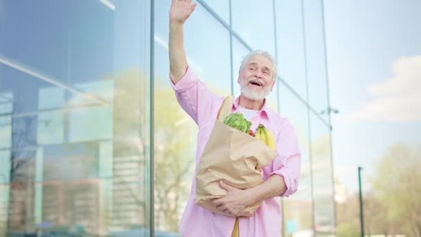 Cheerful Pensioner Going Glassy Building Package Products Waving Hello Friend — Stock Video