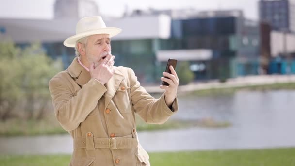 Pensionista Caucasiano Cobrindo Boca Com Mão Choque Assistindo Tela Telefone — Vídeo de Stock