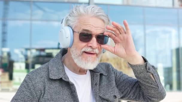 Pensiunan Orang Tua Dengan Headphone Dan Kacamata Hitam Melambaikan Tangan — Stok Video