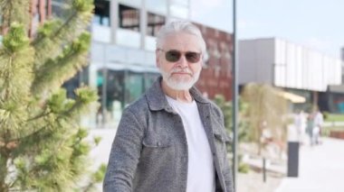 Moda kıyafetli, güneş gözlüklü, kendine güvenen sakallı bir emekli başparmak yapıp gülümsüyor. Aktif yaşlı adamın keyfi yerindeydi. Hayatın tadını çıkarıyordu. Kasabanın dışında durup mutluluğu gösteriyordu..