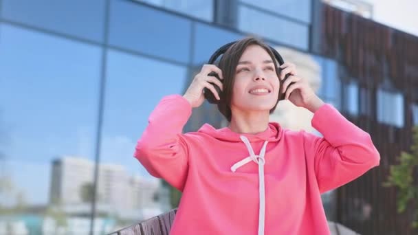 Mooie Vrouw Roze Sweater Die Een Draadloze Koptelefoon Opzet Lekker — Stockvideo