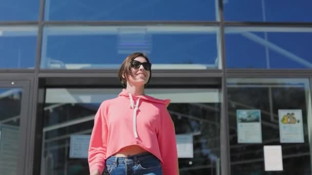 Lässige Frau Gestutztem Kapuzenpulli Und Dunkler Sonnenbrille Verlässt Einkaufszentrum Mit — Stockvideo