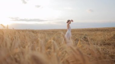 Beyaz elbiseli çekici beyaz kadın üzerine odaklanmıştı. Batan güneşin yumuşak parıltısı altında uçsuz bucaksız altın buğday tarlalarının arasında dans ediyordu. Barış kavramı ve doğa ile uyum.