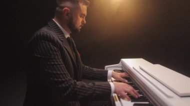 Sakallı ve kısa saçlı bir adam müzik enstrümanında oturup zarif müzikler söylüyor. Yetenekli erkek müzisyen güzel piyanoda yeni bir melodi bestelerken nazikçe klavyelere dokunuyor..