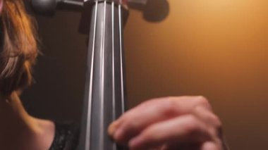 Sahnede otururken müzik aletinin tellerini çalan kadın ellerini kapatın. Muhteşem performans sırasında ünlü çello orkestrasına eşlik eden yetenekli bir müzisyen kadın..