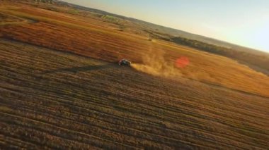 Gün batımında muazzam altın tarlasında çalışan hasatçıyı birleştirin. Açık gökyüzü ve sıcak renkler, iş günlerinin huzurlu sonla bittiğini gösteriyor. Traktör, makine ve teknoloji kavramı.