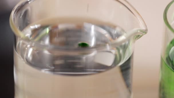 Close Gotas Líquidas Verdes Caindo Água Cima Copo Químico Vidro — Vídeo de Stock