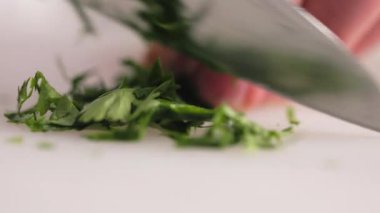 Kesme tahtasında taze yeşil bitkiler doğrayan usta bir şef. Mutfak maestro 'nun elleri restoranda gelecek mutfak başyapıtı için dekorasyon hazırlıyor..