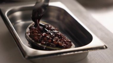 Görünür ızgara izleri olan taze patlıcan ve sulu görünüyor. Yetenekli yemek ustası pişmiş bölgedeki aromatik sebzelerin üzerine metal kaşıkla koyu sos döküyor. Profesyonel mutfak..