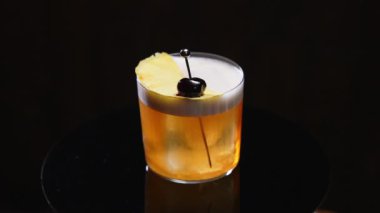 Amaretto ekşi kokteyl, üzeri çırpılmış yumurta beyazı köpükle kaplı ve limon kabuğu ve metal şişte siyah zeytin ile süslenmiş. Narenciye suyuyla karıştırılmış likörden yapılan tatlı ve acı alkol içeceği..