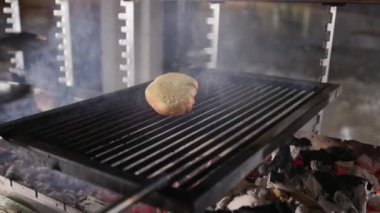 Izgaranın üzerine tek parça ekmek ve görünür çizgi işaretleri. Çöreğin etrafında dumanlar yükseliyor ve taze pişirildiğini gösteriyor. Metalik yapıları olan çağdaş bir mutfak..