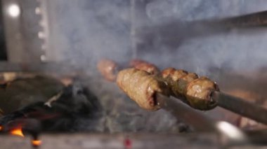 Lyulya-Kebap 'ın açık ateşte kızartılışının yakın görüntüsü. Alevli cızırdayan et ve pişirme sürecinde duman. Geleneksel Gürcü yemekleri.