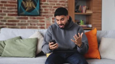 Kapüşonlu ve kot pantolonlu umut dolu erkek oturma odasında telefonla oynarken online kumarhanede zafer için dua ediyor. Çekici bir adam bahsin sonucunu beklerken umutsuzluğa kapılıp geri dönüyor..