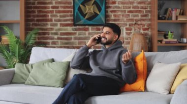 Keyifli bir telefon konuşması yaparken koltukta oturup arkana yaslanan kaygısız bir adam. Rahatlamış erkek el hareketleriyle hikaye anlatıyor ve içtenlikle gülüyor..