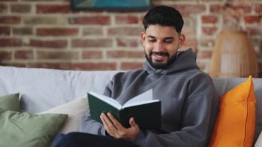 Pozitif ispanyol erkek yastıklı koltukta oturuyor ve evde gün içinde büyüleyici kitaplar okuyor. Genç bir erkek yararlı bir hobi ediniyor ve kurgu edebiyatının heyecanlı öyküsüyle ilgileniyor..