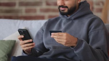 Temassız ödemeyi tamamlayan adamı kapatırken kredi kartındaki verilerin doğruluğunu kontrol et. Rastgele giyinen rahat adam internet sitelerinde parasız işlem hesabının doğruluğunu kontrol ediyor.