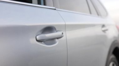 Tişörtlü, kapı kolunu tutan, dışarıda arabaya binen tanınmamış bir adam. Erkek elini kol saati ile kapatarak caddede araba kapısını aç. Seyahat, araba kiralama, iş, seyahat kavramı.