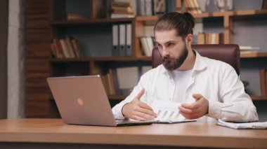 Kendine güvenen iş adamı merkez ofiste video konferansı yapıyor. Orta yaşlı yöneticinin online konuşması, baş parmağını kaldırması, yumruklarını kaldırması, harekete geçmesi. İş, uzak çalışma konsepti.