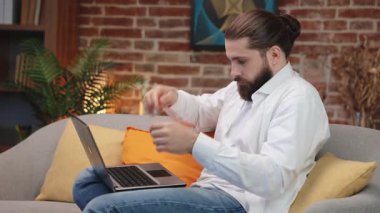 Odaklanmış, uzun saçlı, dizüstü bilgisayarında yazan bir adam. Kot pantolon ve gömlek giyen, fikir sahibi, evde uzaktan çalışan, hareket halinde, ilham verici erkek serbest görüşlü. Uzak çalışma konsepti.