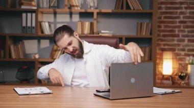 Dizüstü bilgisayardaki işi bitirdikten sonra mutlu iş adamları dans ediyor. Ahşap masada otururken harika iş sonuçları aldıktan sonra sevinen neşeli beyaz adamın portresi. İş yeri, başarı kavramı.