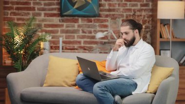 Saçları bağlanmış yakışıklı bir adam dizüstü bilgisayar ekranına bakarken çenesini dinlendiriyor. Derin düşüncelere dalmak ya da ciddi kararları değerlendirmek. Sessiz bir odada karmaşık bir göreve daldım..