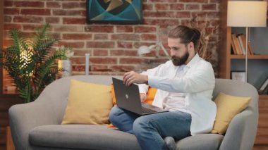 Odaklanmış beyaz gömlekli beyaz adam kanepeye oturmuş dizüstü bilgisayarını açıyor ve yazmaya başlıyor. Uzaktan kumandaya ya da internet haberleşmesine hazırlanıyorum. Sakin ev ortamında dijital görev başlatılıyor.