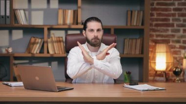 Kafkasyalı bir adam masanın arkasında oturuyor ve önünde kollarını kavuşturuyor. Öneri engelleme ya da talimatları reddetme. Ofis tartışması sırasında katı anlaşmazlıklar.