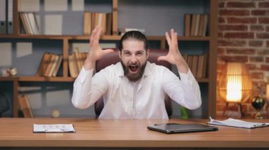 Kafkas 'lı mutlu adam yumruklarını kaldırıyor ve masaya gülümseyerek bağırıyor. Büyük zaferi kutlamak ya da harika haberlere tepki vermek. Sanal başarı ya da duyuru sırasında saf mutluluğu göstermek.